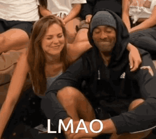 a man and a woman are sitting next to each other and the man is wearing a hooded sweatshirt with the word adidas on it