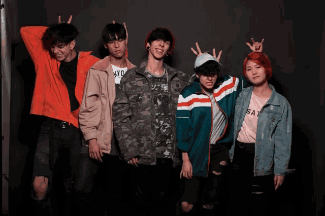 a group of young people are posing for a picture with one wearing a shirt that says sat