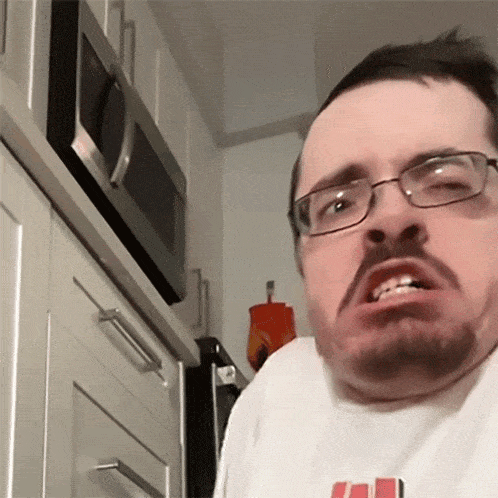 a man with glasses and a beard wears a white shirt that says ' uc ' on it
