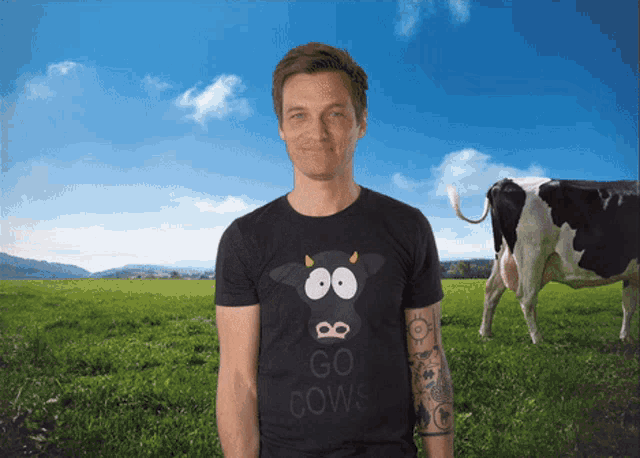 a man in a go cows shirt stands in a field