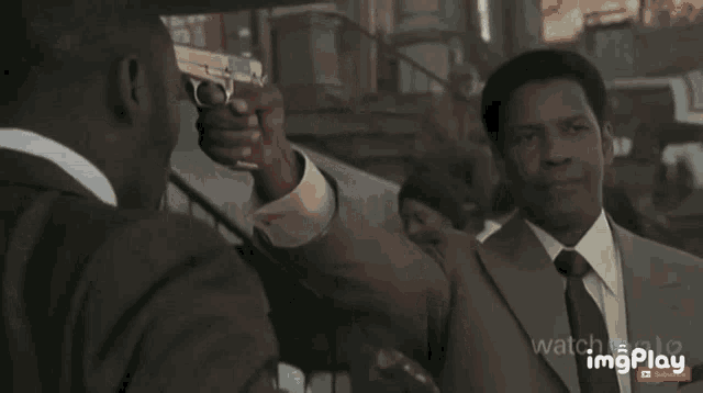 a man in a suit and tie holds a gun in front of a barber shop