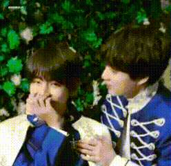 two young boys are sitting next to each other eating food .