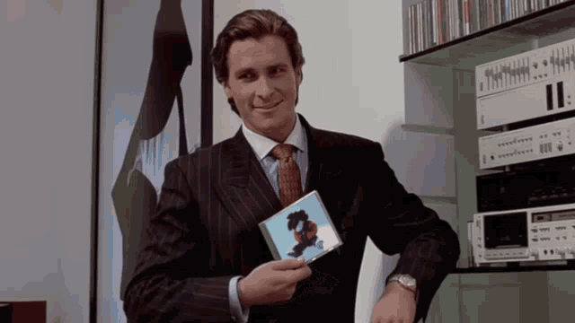a man in a suit and tie is holding a cd in his hand
