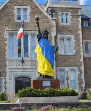 a statue of the statue of liberty with a yellow and blue flag draped over her