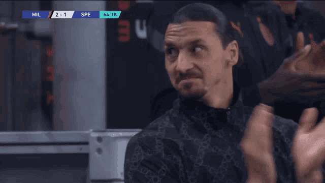 a man sitting in front of a scoreboard that says milan 2-1 spe 64:19