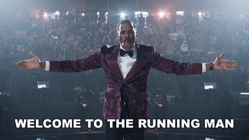 a man in a purple tuxedo is standing in front of a crowd with the words welcome to the running man written below him