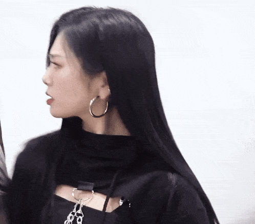 a woman with long black hair wears hoop earrings