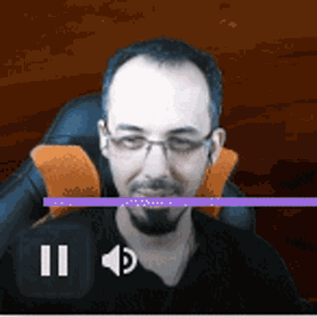 a man with glasses and a beard is sitting in a chair with a purple line between him and the pause button .