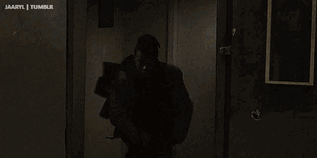 a man in a blue shirt is holding a bow and arrow in a dark room with the words " jaaryl tumblr " above him