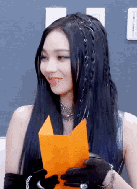 a woman with long black hair is holding a piece of paper