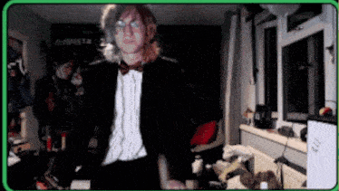 a man in a tuxedo and bow tie stands in a room