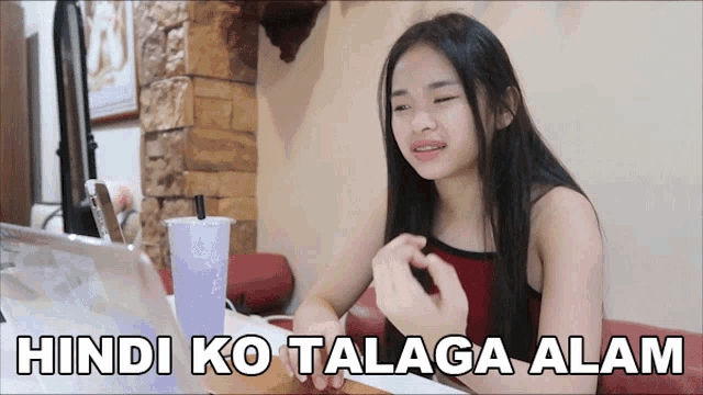 a girl is sitting at a table with a laptop and the words hindi ko talaga alam written on the bottom