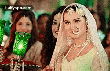 a woman in a wedding dress and veil is standing in front of a group of women .