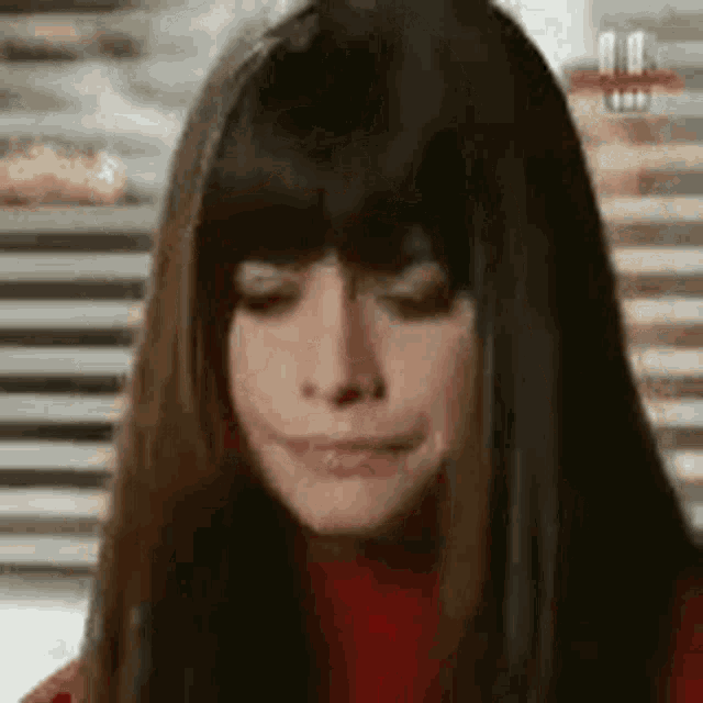 a woman with long dark hair and bangs is making a funny face .