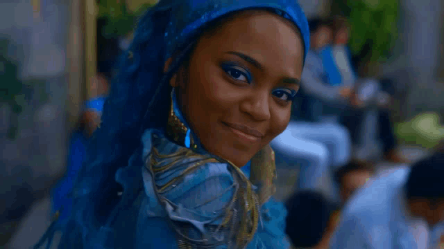 a woman with blue hair is smiling for the camera while wearing a blue dress .