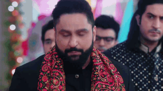 a man with a beard and a scarf around his neck is standing in a line with other men .