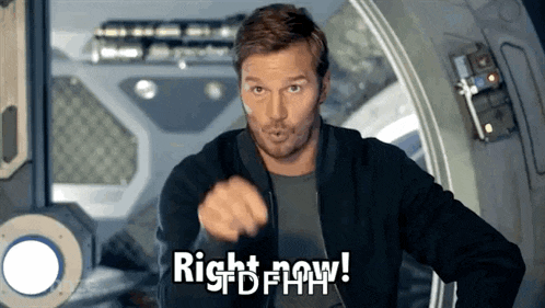 a man in a black jacket is pointing at the camera with the words right now written below him