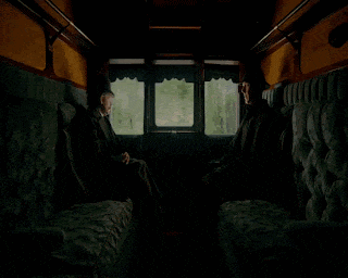 two men are sitting in a dark room talking to each other