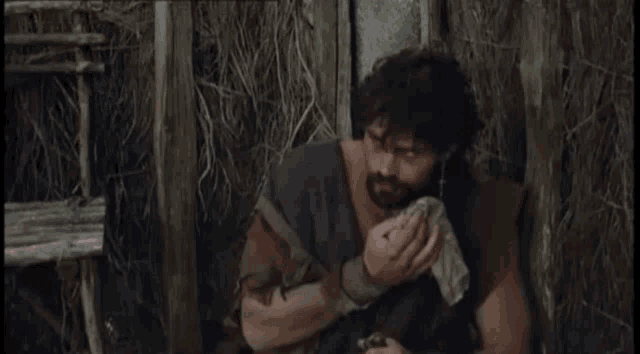 a man with a beard is holding a piece of wood and talking to another man