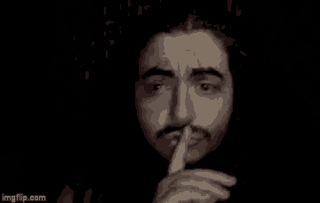 a man with a beard and mustache is holding his finger to his lips .