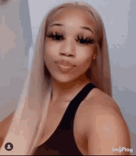 the woman is wearing a black tank top and has long blonde hair .