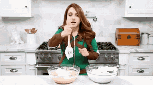 a woman is standing in a kitchen holding a spoon