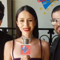 a woman is holding a microphone in her hand and smiling while standing next to two men .