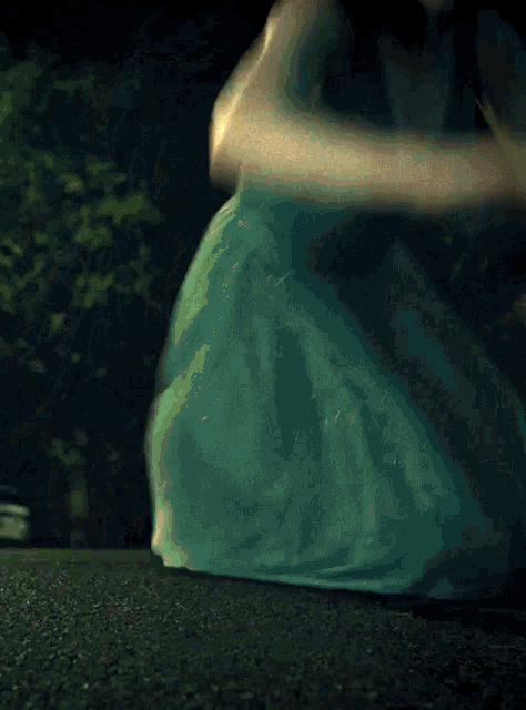 a woman in a green dress is sitting on the ground at night