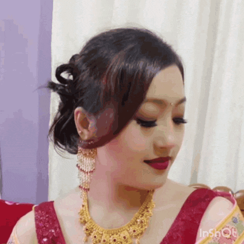a woman wearing a gold necklace and earrings is sitting on a couch