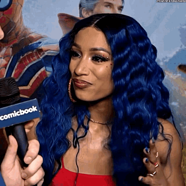 a woman with blue hair is holding a microphone that says comicbook on it