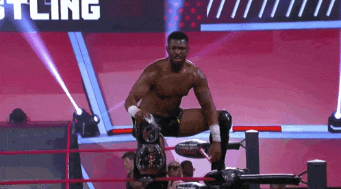 a wrestler is kneeling down in a wrestling ring with the word wrestling in the background