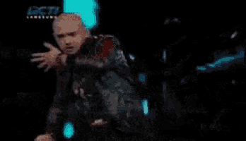 a person is standing on a stage in a dark room with a sign that says get .