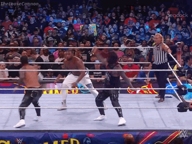 a group of wrestlers are fighting in a wrestling ring while a referee looks on .