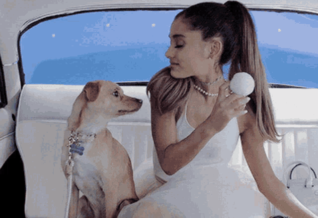 a woman is sitting in the back seat of a car with her dog