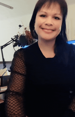 a woman is smiling in front of a microphone in a room