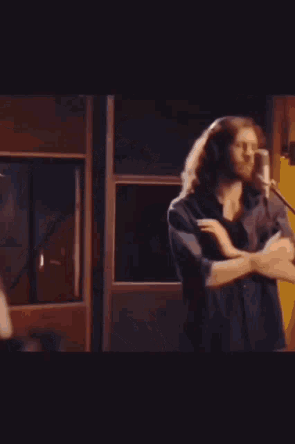 a man with long hair singing into a microphone