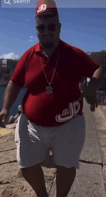 a man wearing a red shirt with a dollar sign necklace