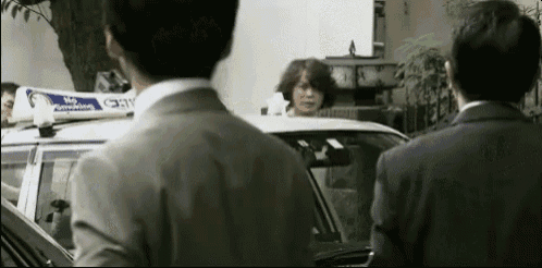 a man in a suit is standing in front of a taxi with a sign on top that says no smoking