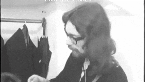 a black and white photo of a man with glasses and long hair