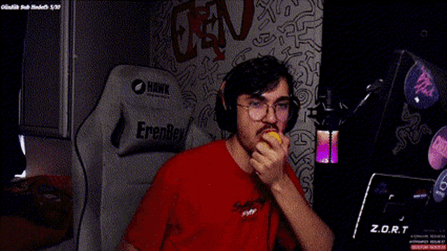 a man wearing headphones and a red shirt is sitting in a chair holding a microphone .