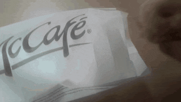 a person is holding a piece of paper with the word mccafe on it