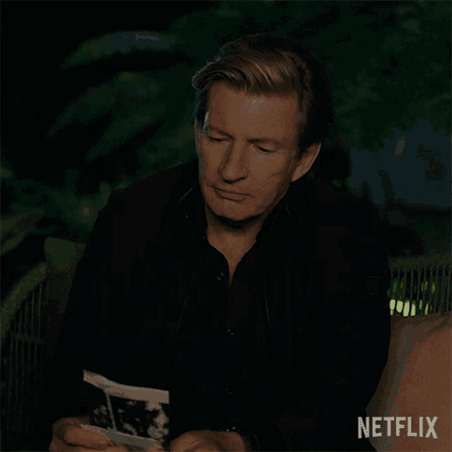 a man in a black shirt is holding a piece of paper that says no on it