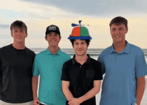 four young men are posing for a picture with one wearing a hat that looks like a propeller