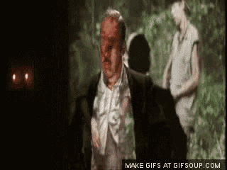 a man with blood on his face is running in a dark room with a woman behind him .