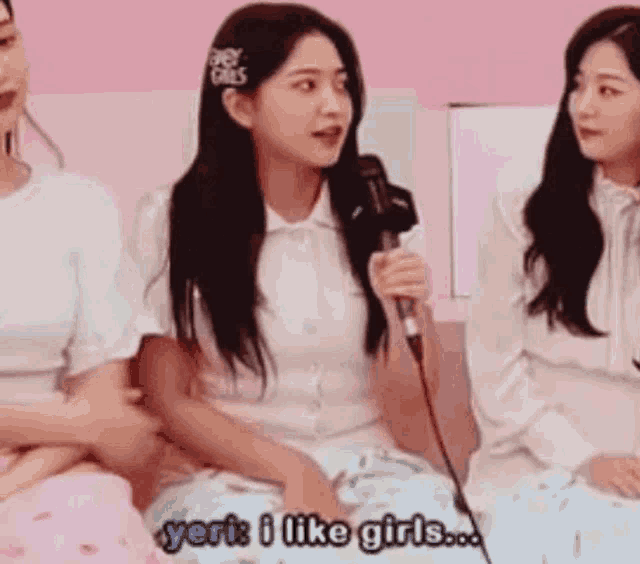 a woman is holding a microphone and talking to a group of girls .