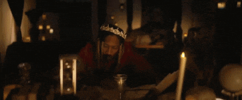 a man with dreadlocks and a crown on his head is standing next to a woman .
