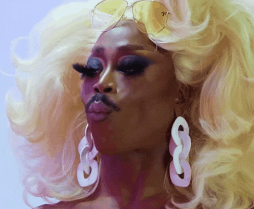 a woman with blonde hair and earrings has a mustache