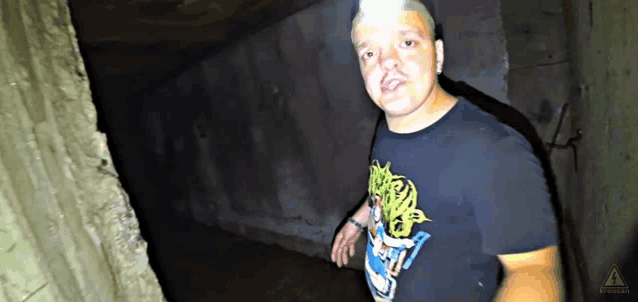 a man wearing a t-shirt that says ' apocalypse ' on it stands in a dark room