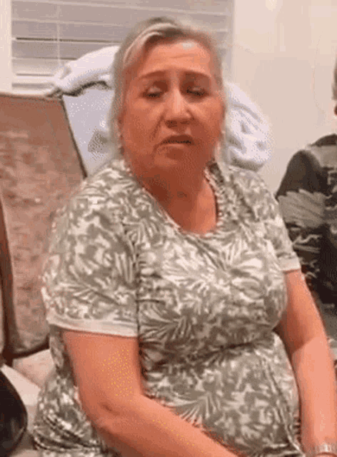 a woman in a green and white shirt is sitting in a chair and looking at the camera .