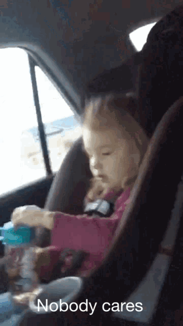 a little girl sitting in a car seat with the words " nobody cares " on the bottom
